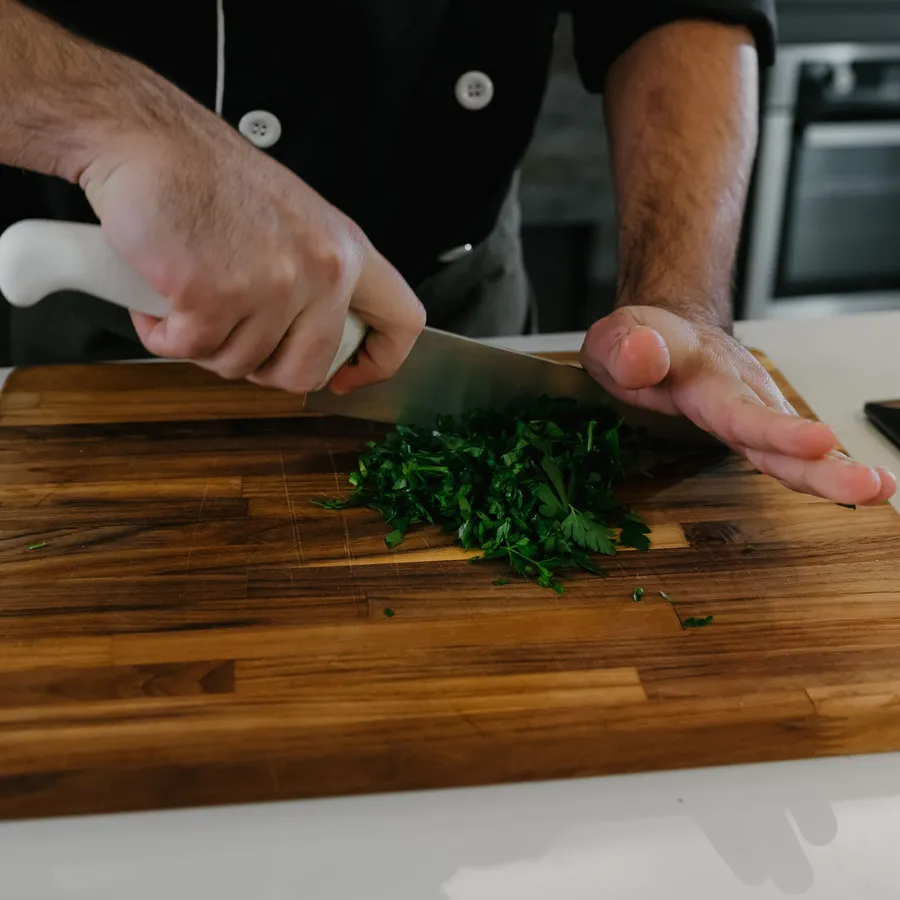 Chef chopping fresh herbs on a wooden board